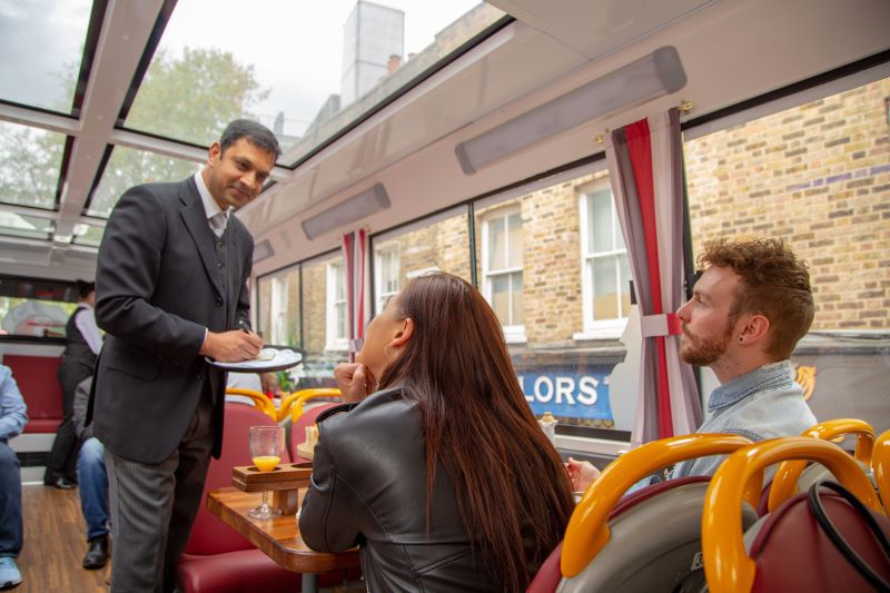 Server speaking to guests on Afternoon Tea Bus London