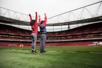People cheering on the Arsenal pitch in the Emirates Stadium