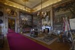Darkly lit State Room at Blenheim Palace with red carpets and walls covered in scenery paintings and gold dipped furnishings