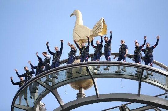 Group of people dressed in safety harnesses cheering from top of The Dare Skywalk