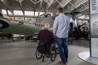 Man standing next to man in wheelchair next to display at the Imperial War Museum Duxford