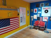 Blue painted wall covered in museum exhibition displays next to small Statue of Liberty replica in room at Liverpool Beatles Museum
