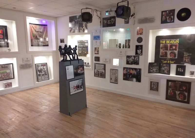 Room with white painted walls covered in pictures and displays at Liverpool Beatles Museum