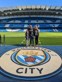 Group of three family members stood together on the pitch at Manchester City Stadium
