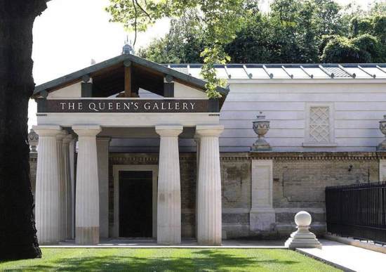 Historic building with four white pillars beneath engraved name 'The Queen's Gallery' in front of grassy patch and tree on a sunny day