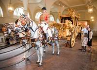 Gold state coach at Royal Mews, horses with armory on pulling gold carriage