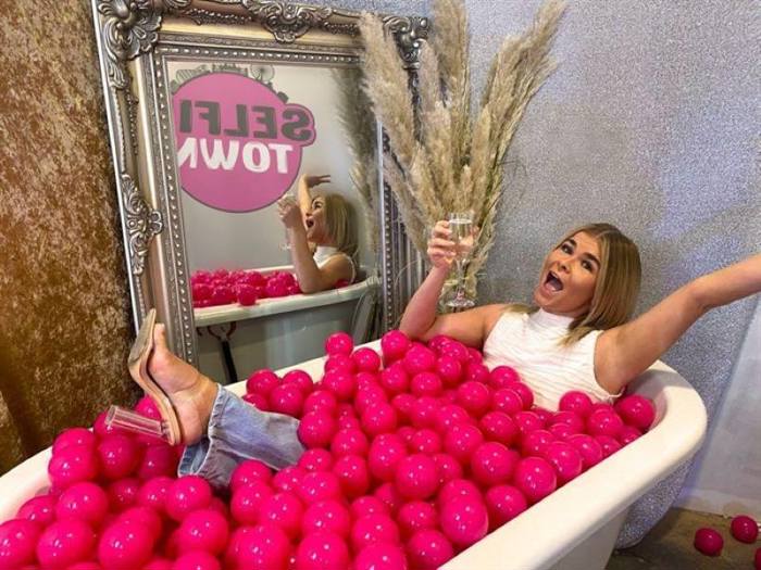 Woman ball pit bath posing for picture with glass of champagne at Selfie Town Blackpool 