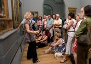 A group of people listening to a tour guide in a gallery