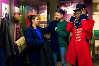 Three people dressing up in costumes at the postal museum