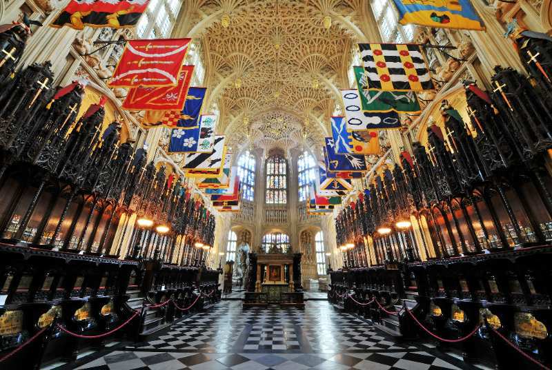 Interior or Westminster Abbey Lady Chapel with chequered tile flooring and flags hung from detailed, carved ceiling