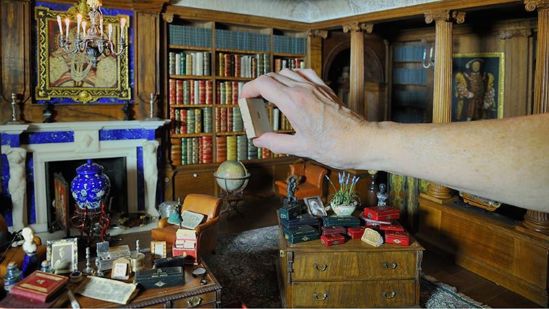 Hand placing miniature furniture in Queen Mary's Dolls' House at Windsor Castle